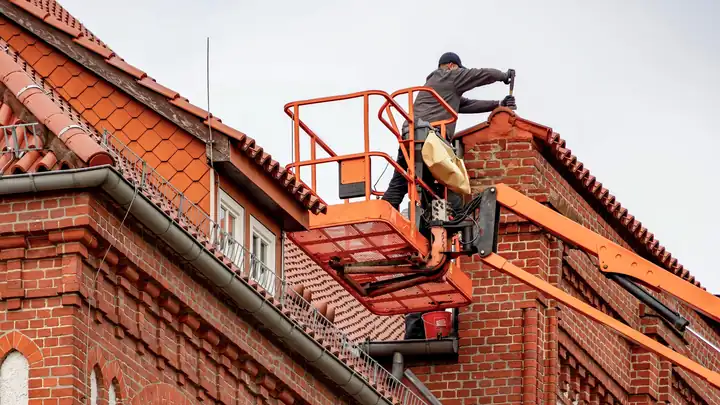 Couvreur posant des tuiles sur la toiture d’une maison en Île-de-France