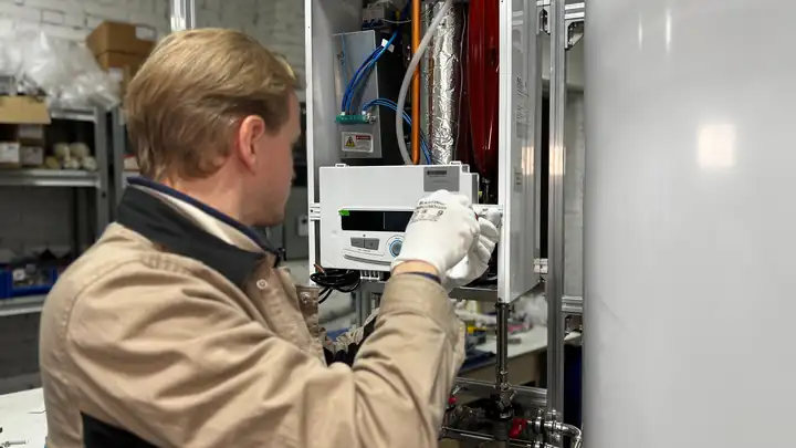 Technicien chauffagiste en dépannage sur une chaudière murale gaz ouverte