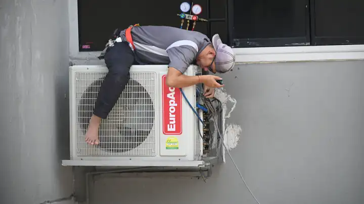 Technicien frigoriste installant une unité intérieure de climatisation murale