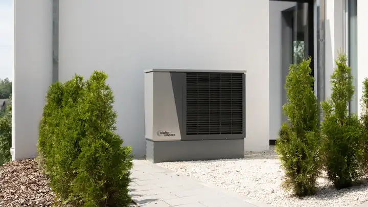 Unité extérieure de pompe à chaleur air-eau installée contre le mur d’une maison