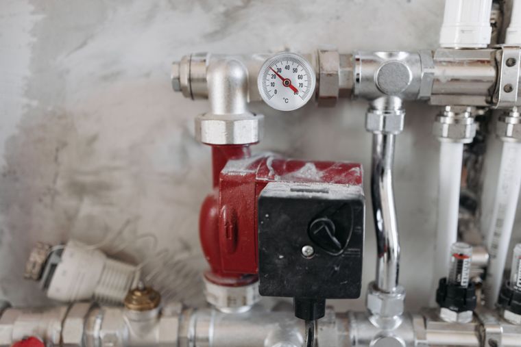 Plombier en train de vérifier un chauffe-eau électrique et ses raccordements
