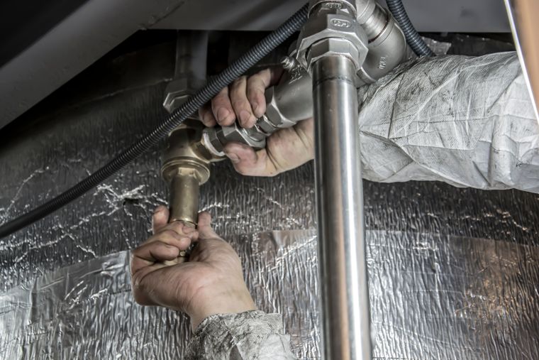 Plombier réparant une fuite d’eau sur les raccords sous un évier